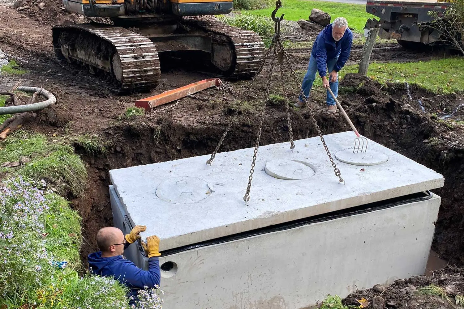 Septic installation crew placing a new septic tank and preparing the drain field