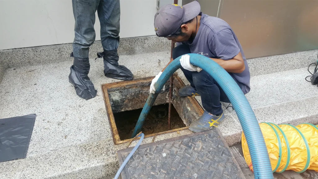 Technician performing grease trap pumping and maintenance to keep a commercial kitchen system clean